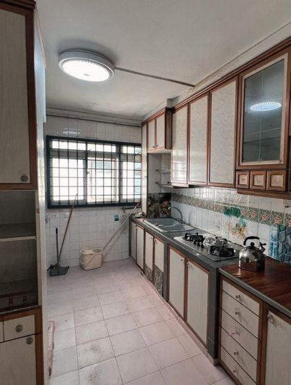 Before: a cramped 1980s HDB galley kitchen with dark timber-trim cabinets and a patterned tile splashback.