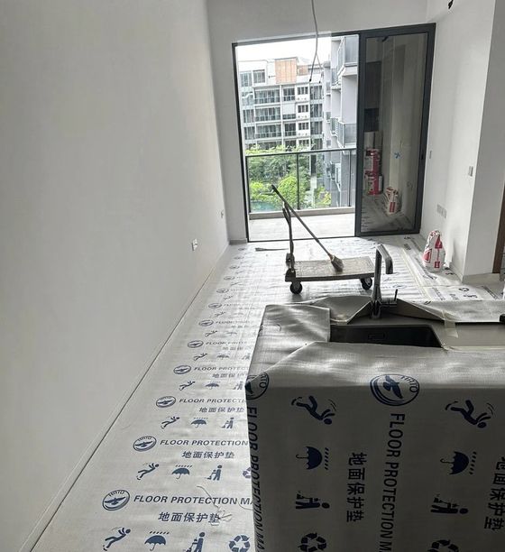 Printed floor-protection matting laid wall to wall in a flat, with the worktop and sink wrapped before work starts.
