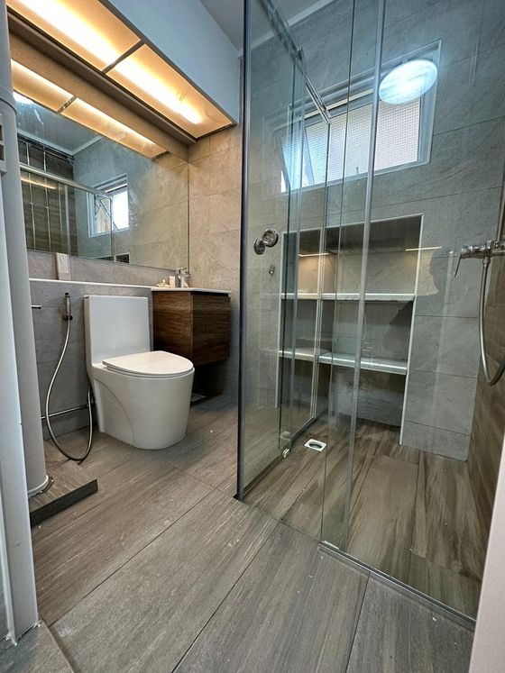 Finished bathroom with a frameless glass shower screen, large-format stone-look tile and a recessed niche.