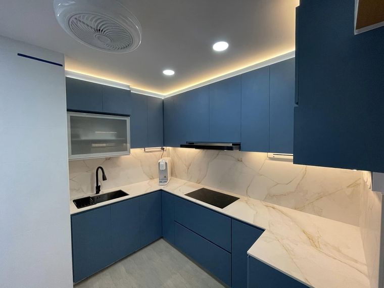 Navy-blue handleless kitchen wrapping three walls, with a white marble-veined worktop and splashback.