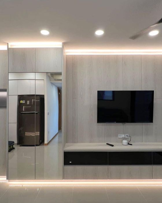 Living room TV feature wall in pale oak with a black-drawer console, cove lighting and a full-height mirrored cabinet.