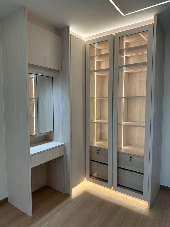Bedroom carpentry in pale ash: a mirrored dressing table beside two glass-fronted LED-lit display wardrobes.